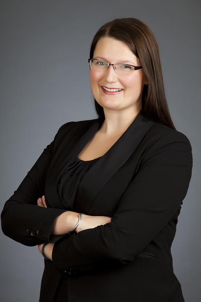 Young professional female posing for a studio headshot photograph in Auckland against a plain grey background