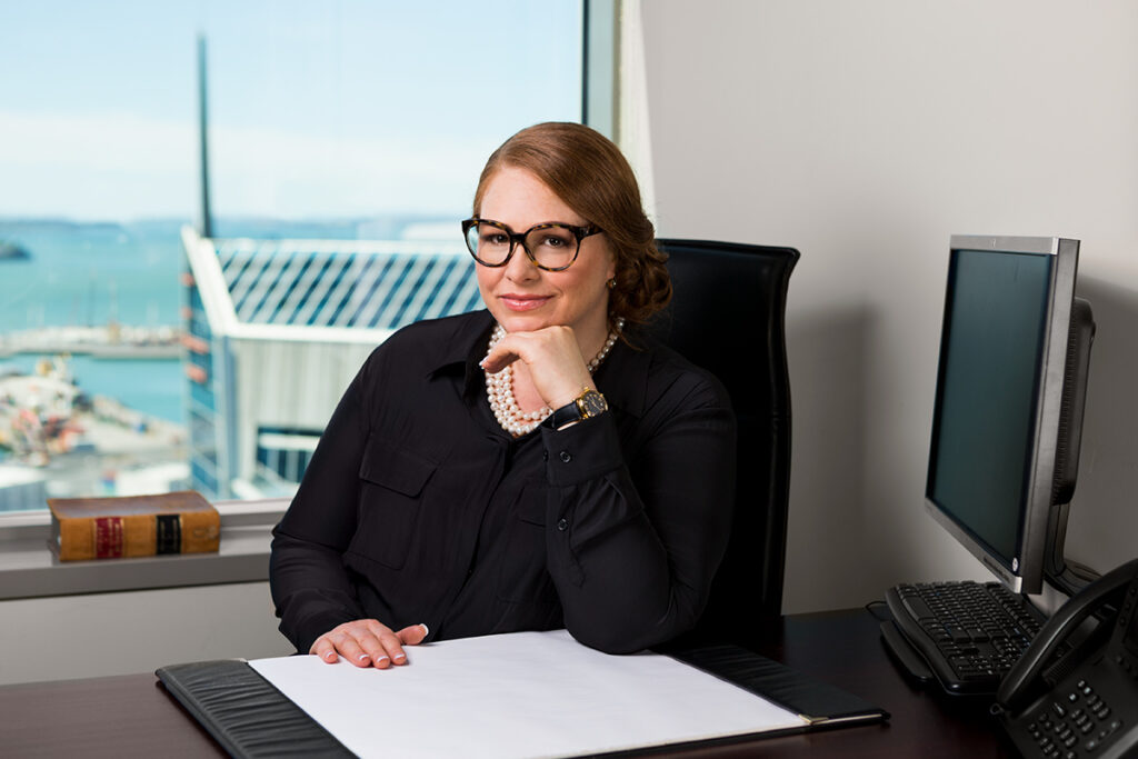 Lawyers headshot captured with a stunning Auckland harbour view behind her desk