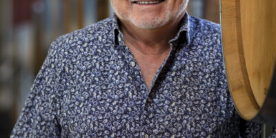 headshot of wine maker in Auckland standing next to wine barrels