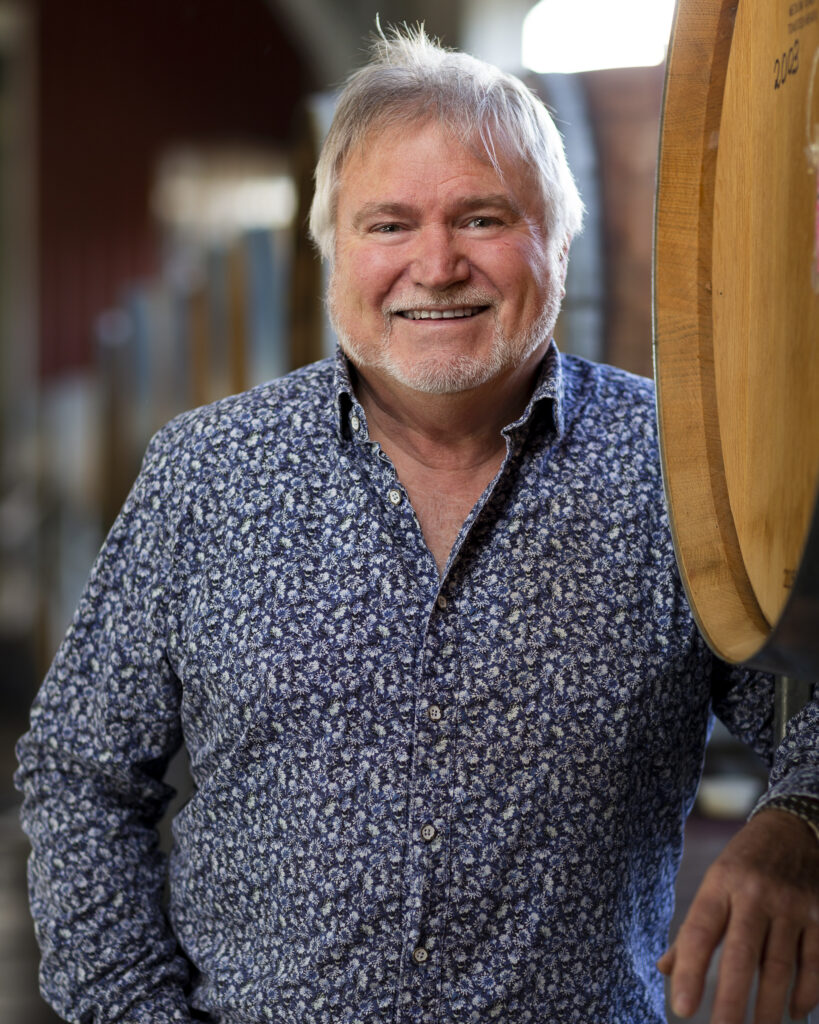 headshot of wine maker in Auckland standing next to wine barrels