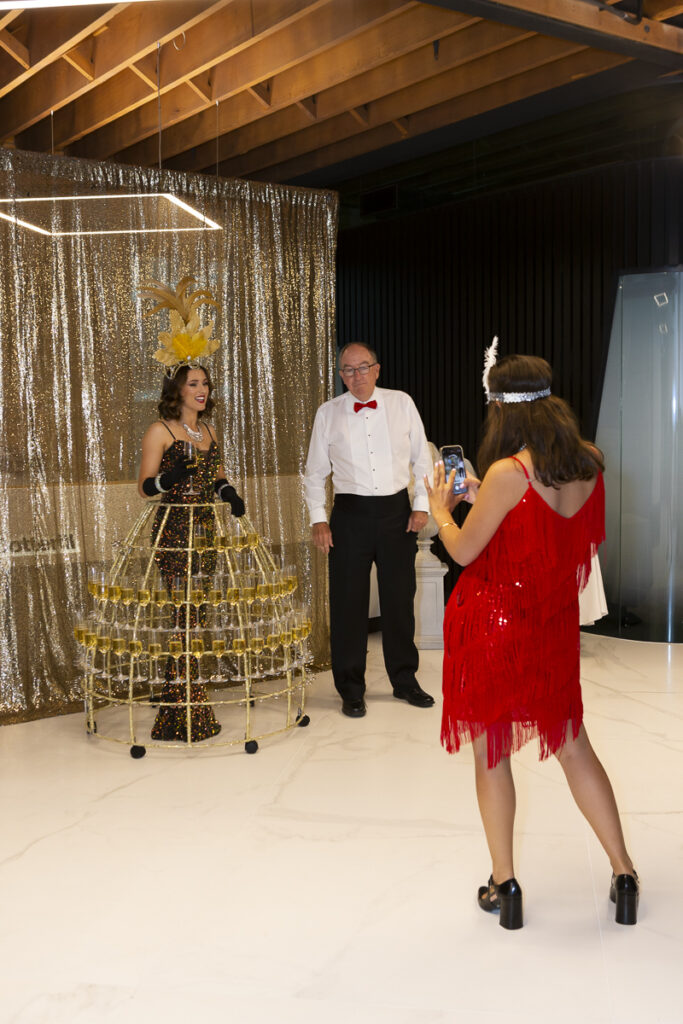 Event photography in Auckland showing girl beingn photographed while wearing champaign wire dress