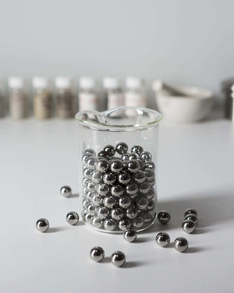 beaker with metal ball bearings and products in containers standing behind 