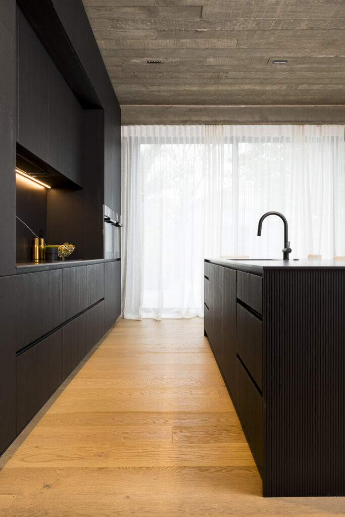 Interior architectural photograph straight down the line of a dark kitchen in Ponsonby Auckland