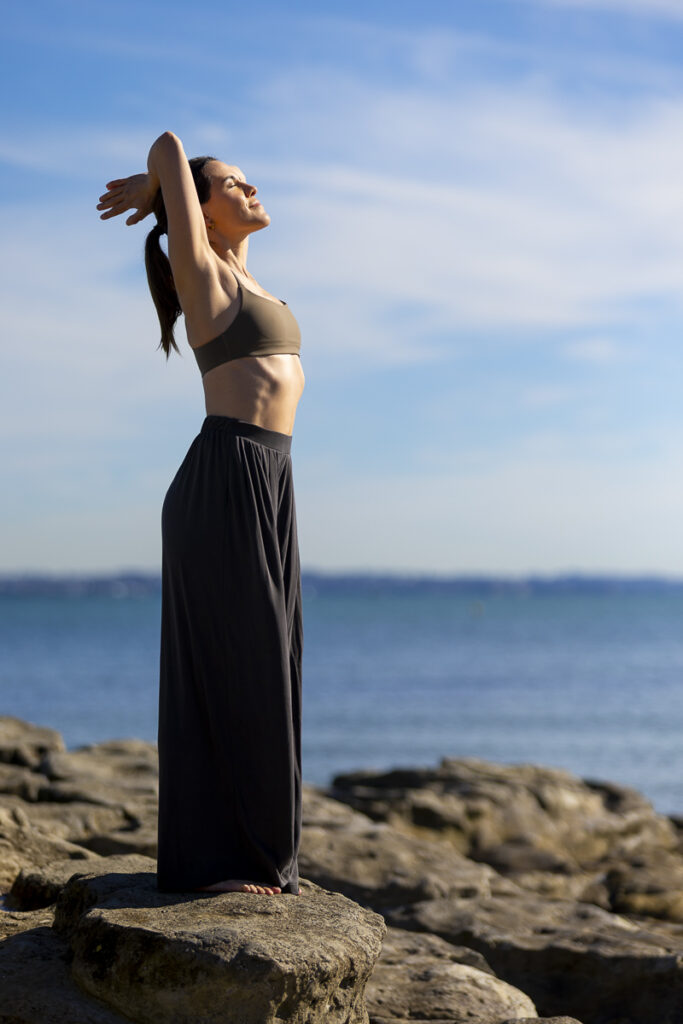 Greeting the sun. Photograph of yoga instructor concentrating on her breath and the warmth of the morning sun. Photographed by professional photographer Adam Firth at Saint Heliers beach in Auckland.