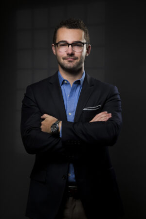 Studio headshot of an Auckland based writer. Captured on a dark grey background with the effect of a window on the plain background created by a lighting gobo. Captured in Kohimarama, Auckland by photographer Adam Firth