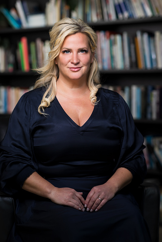 headshot photograph captured during a photoshoot for NIB insurance, blond haired lady sitting in front of library wall
