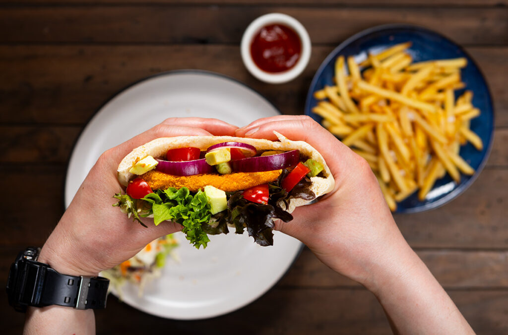 a yummy pita bread filled with chicken patty photographed above chips and sauce photographed by Adam Firth