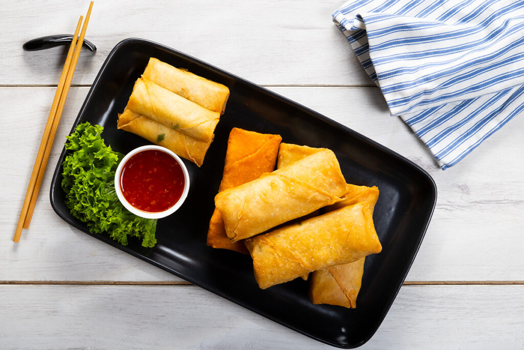 spring rolls photographed on a black plate on a white background by Adam Firth an Auckland professional photographer